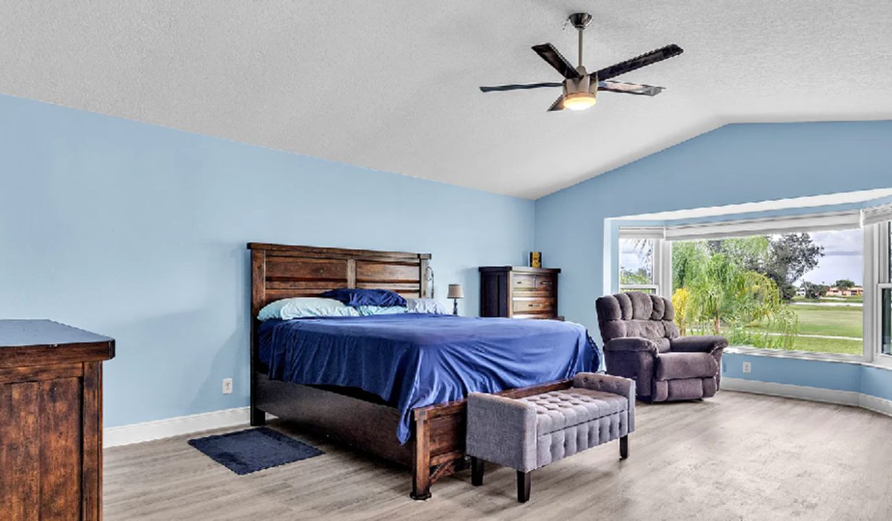 Une chambre à coucher avec un lit, une chaise, un bureau et une fenêtre donnant sur un beau paysage.