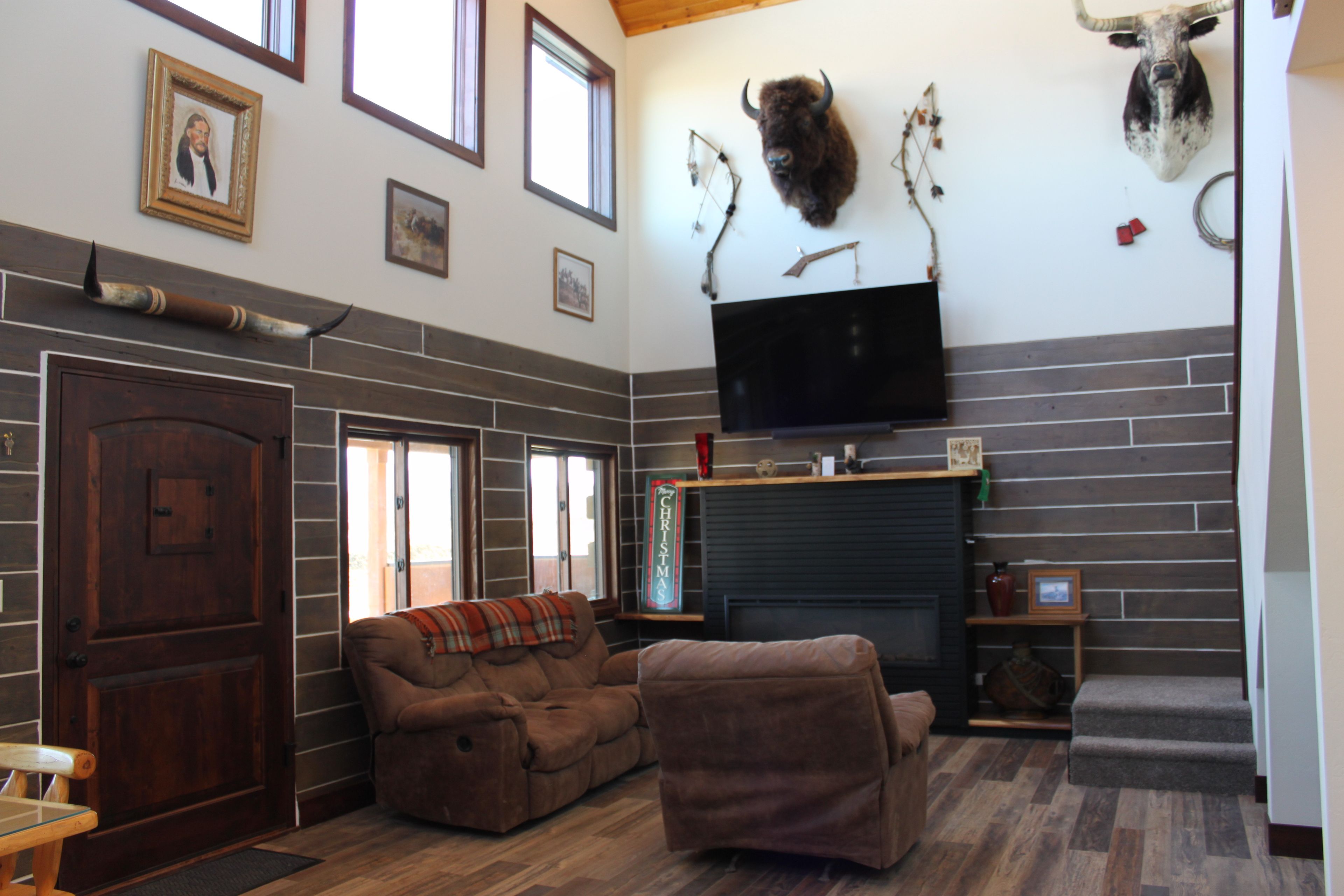 A living room with a fireplace, a sofa, a television, and mounted animal heads on the wall.