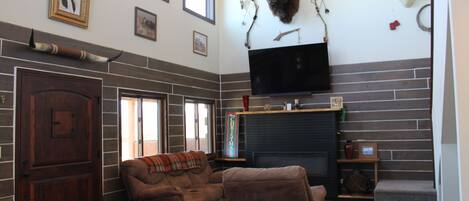 A living room with a fireplace, a sofa, a television, and mounted animal heads on the wall.