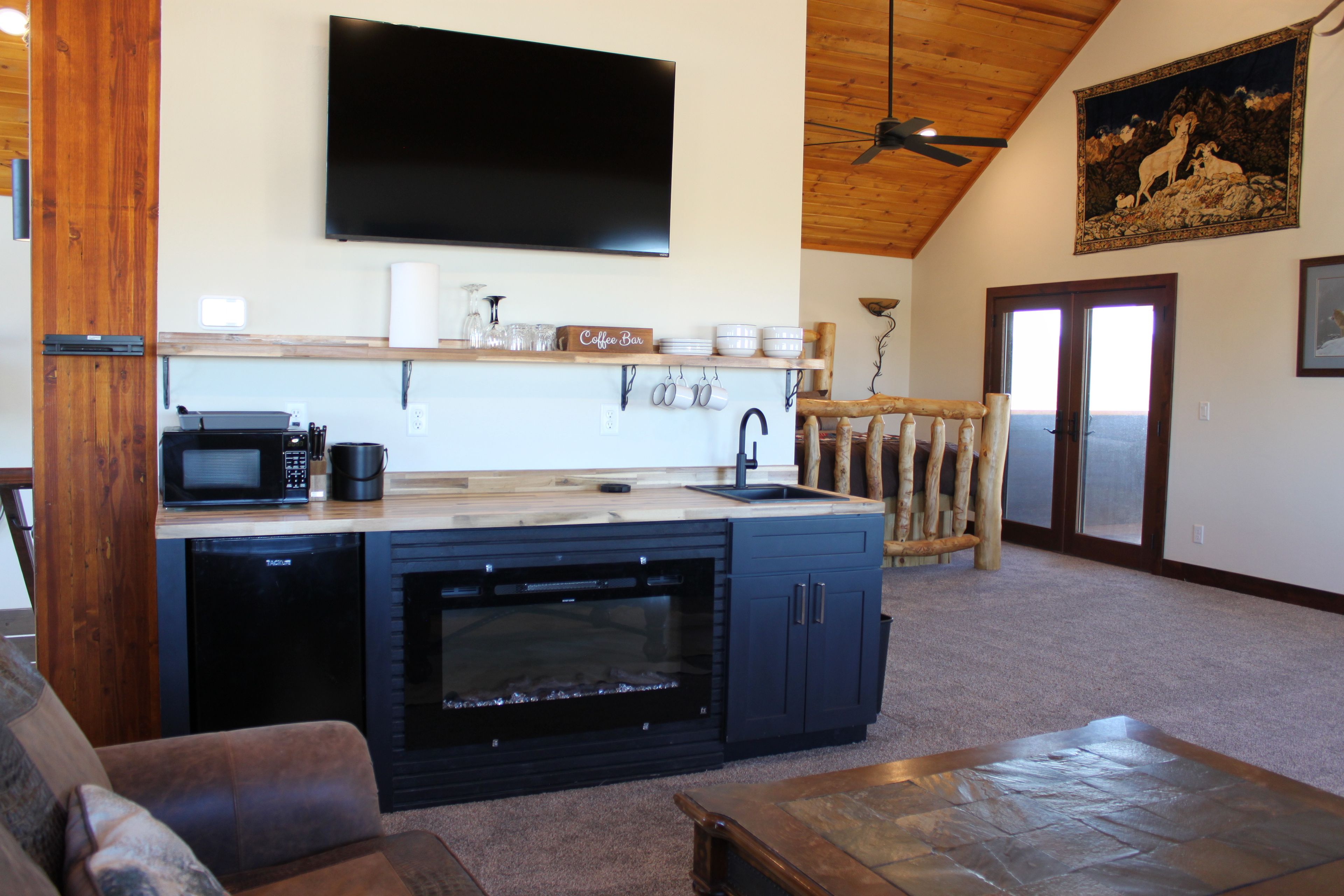A modern kitchen with a flat-screen TV, a coffee bar, and a stone countertop.
