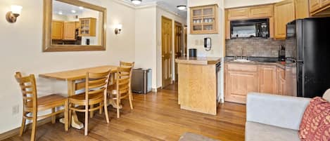 A compact living space with a dining area, kitchenette, and a sofa.