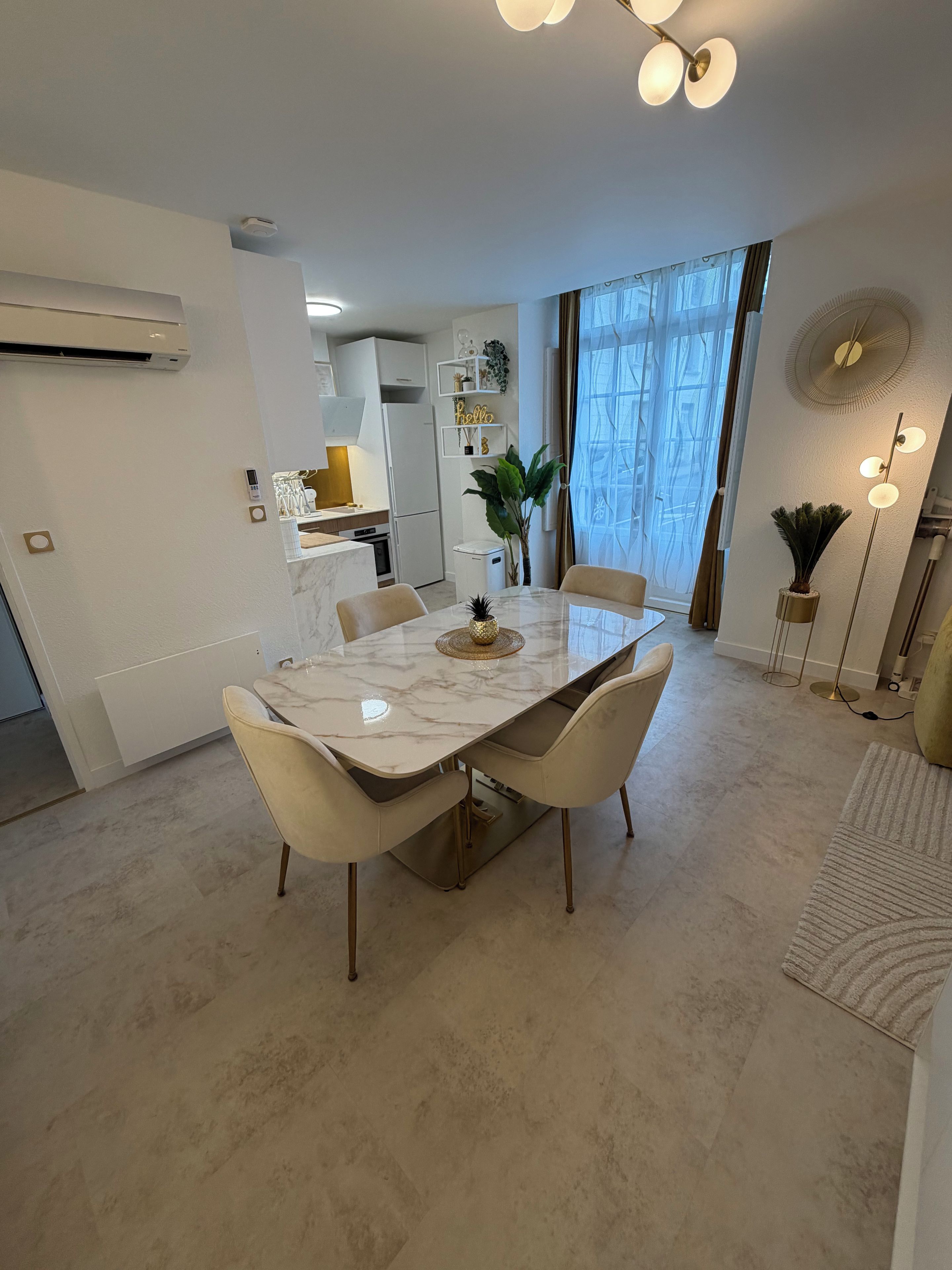 A modern dining area with a marble table, four chairs, and a decorative centerpiece.