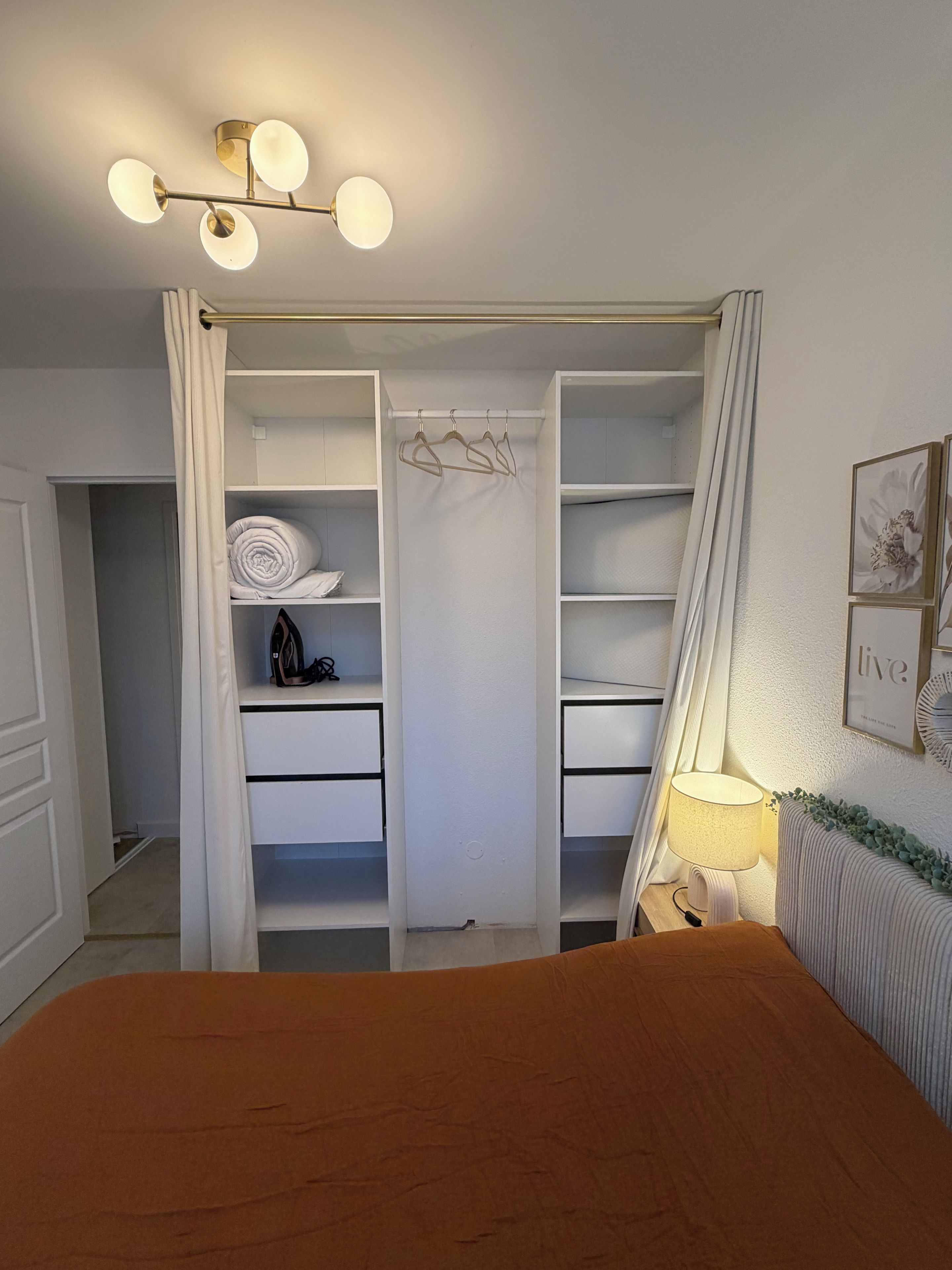 A bedroom with a bed, a wardrobe, and a bedside table with a lamp.