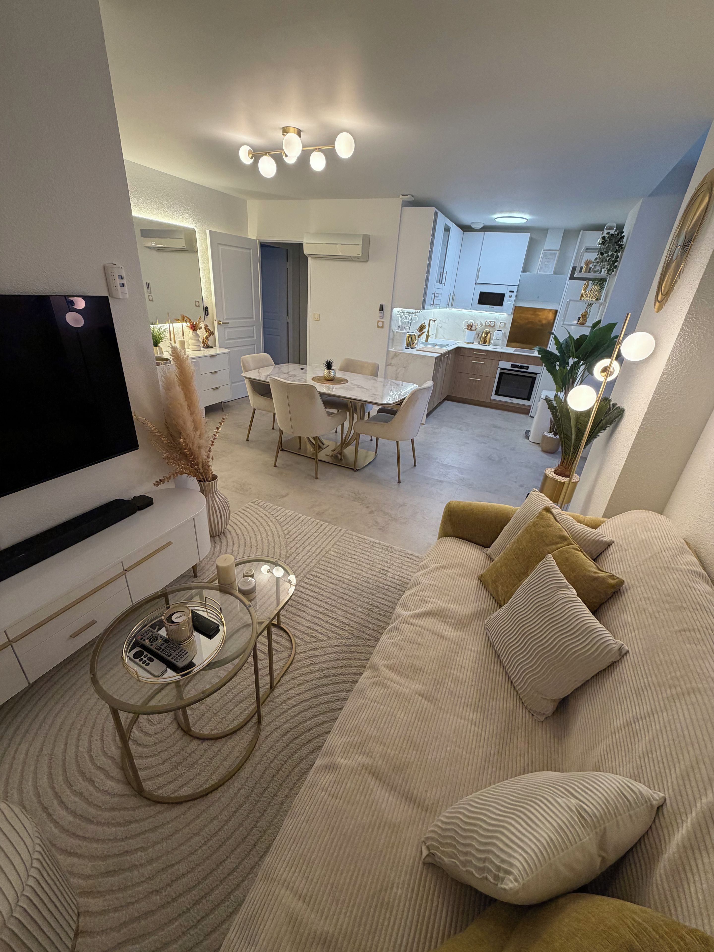 A modern living room with a television, sofa, coffee table, and dining area.