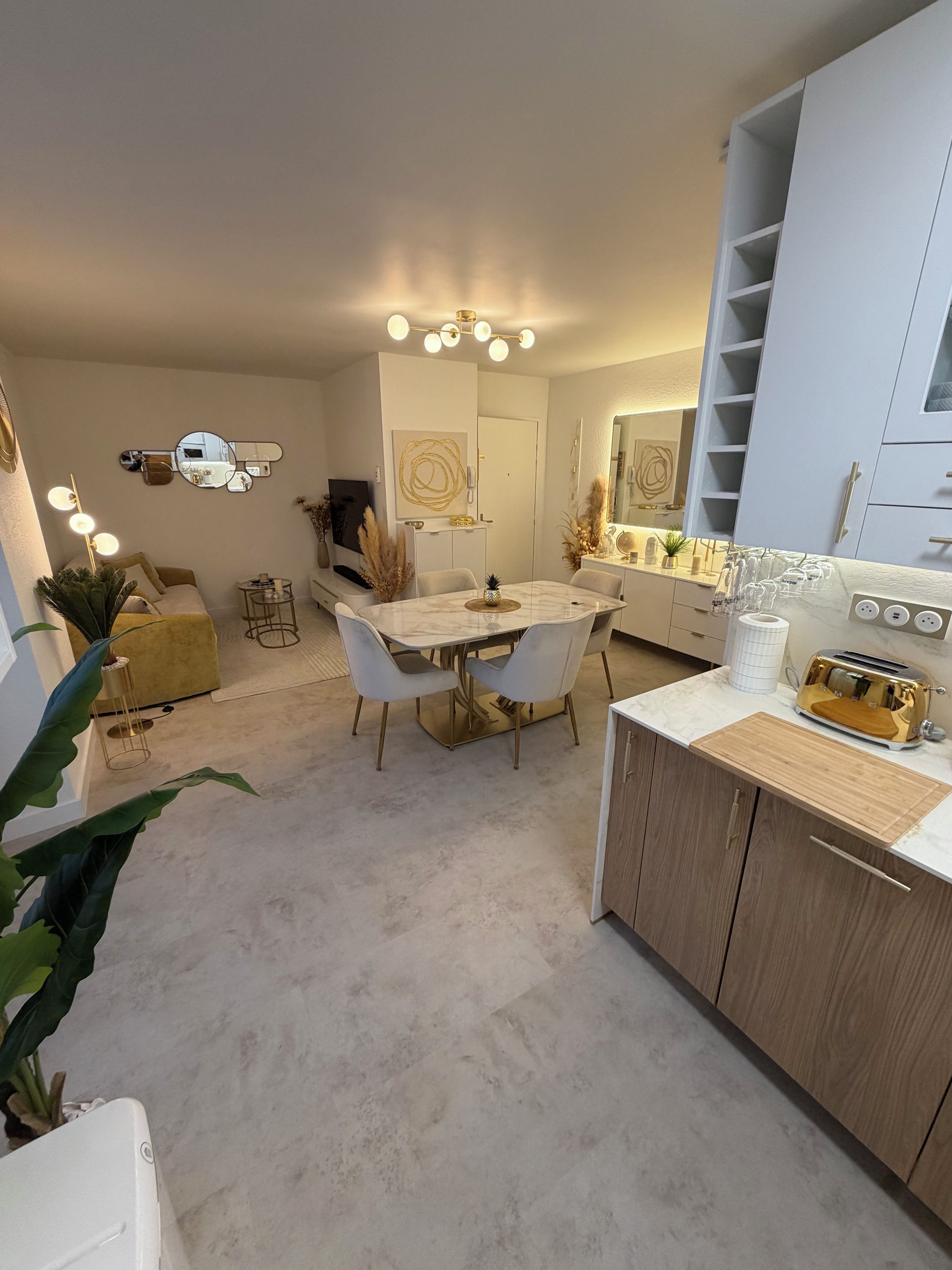 A modern kitchen with a marble countertop, wooden cabinets, and a gold toaster.