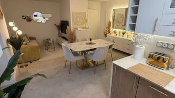 A modern kitchen with a marble countertop, wooden cabinets, and a gold toaster.
