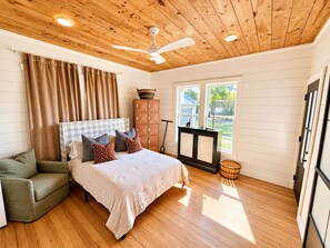 A bedroom with a bed, a green armchair, a wooden ceiling, and a window with a view of the outside. - Charming 3BR Getaway Sleeps 6 Pet Friendly 35 Min to Round Top (Schulenburg)