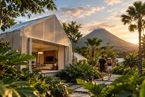 A modern house with an open-plan living area, a TV, and a view of a mountain. - Humaya (La Fortuna)