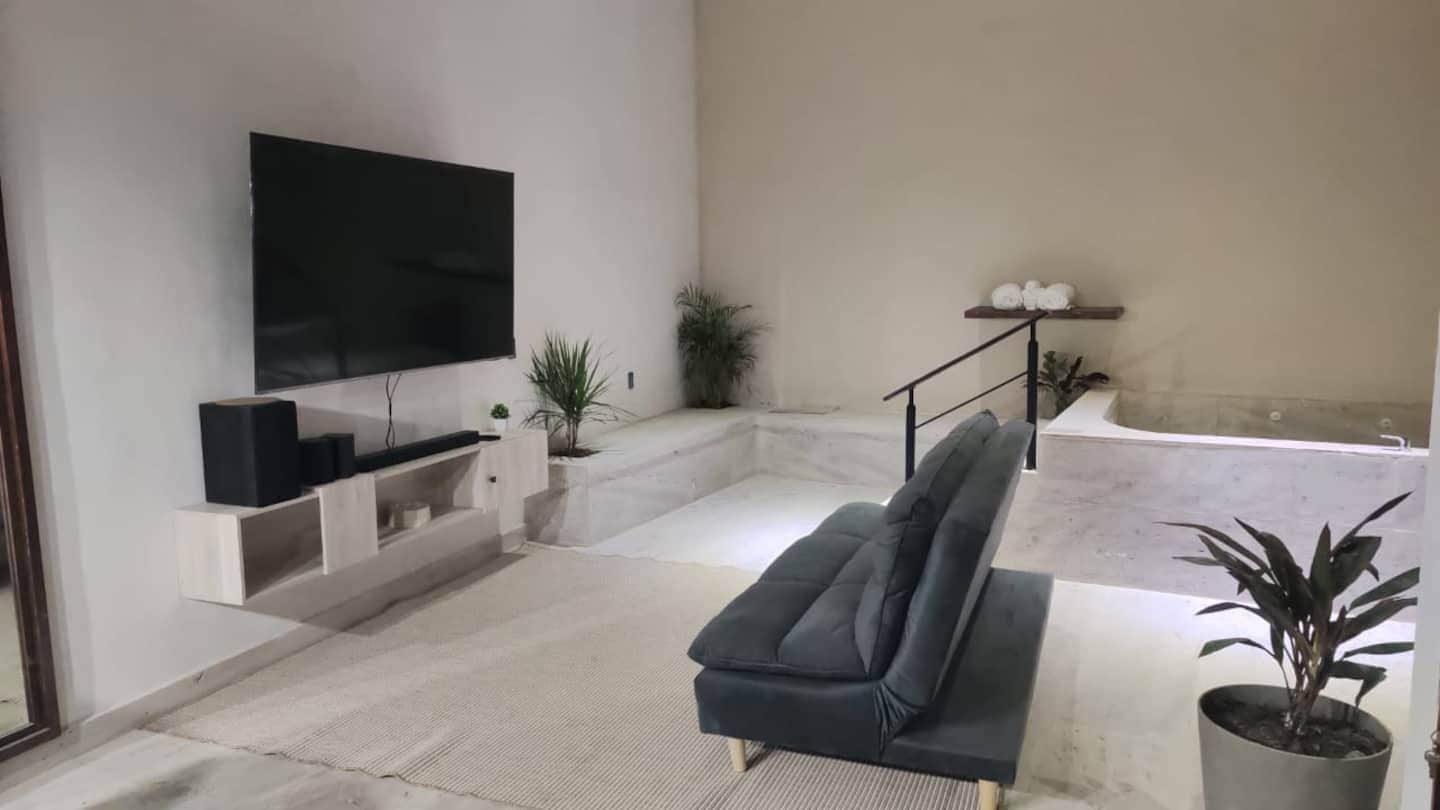Moderni olohuone, jossa on taulutelevisio, sohva ja pienet portaat, jotka johtavat parvekkeelle.