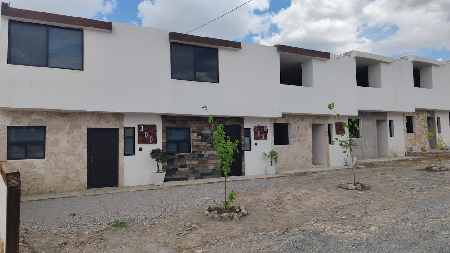 Una hilera de edificios residenciales modernos, de varios pisos, con números en las puertas y plantas en macetas al frente.