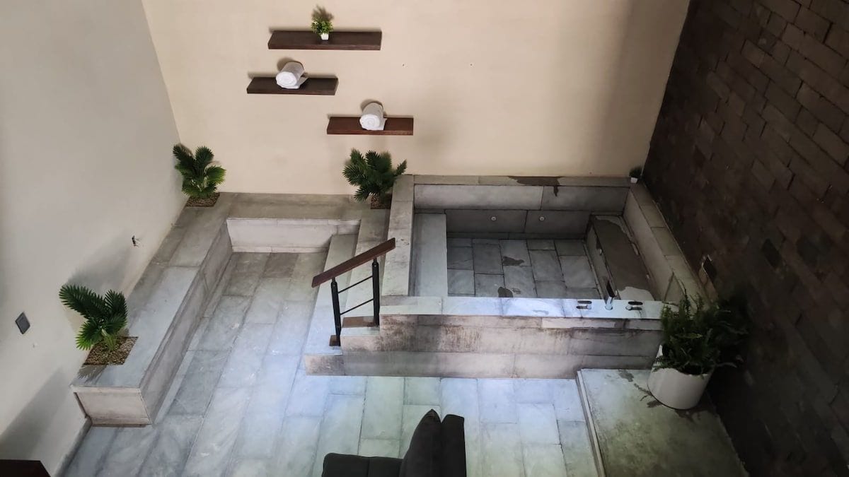 A courtyard with a stone bench, potted plants, and a staircase.