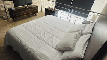 Un dormitorio moderno con una cama grande, un televisor y una pared de piedra.