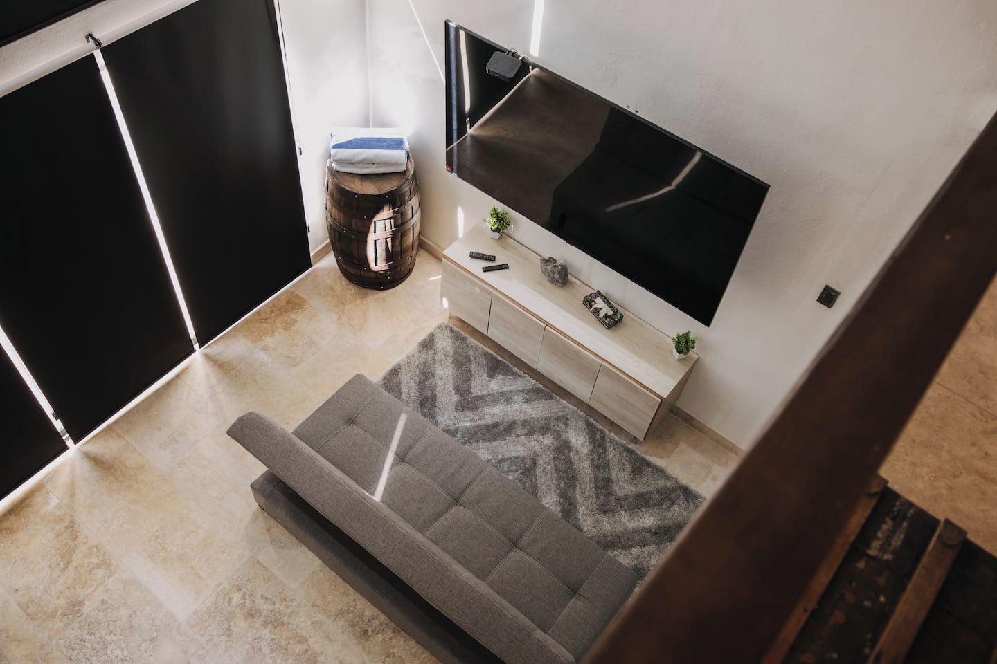 Una sala de estar moderna con un sofá, una televisión, una mesita y un barril decorativo.