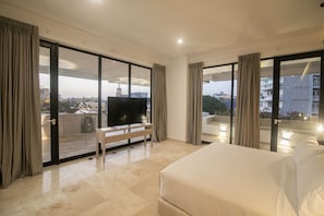 Una habitación de hotel moderna con una cama grande, un televisor de pantalla plana y un balcón con vistas a la ciudad.