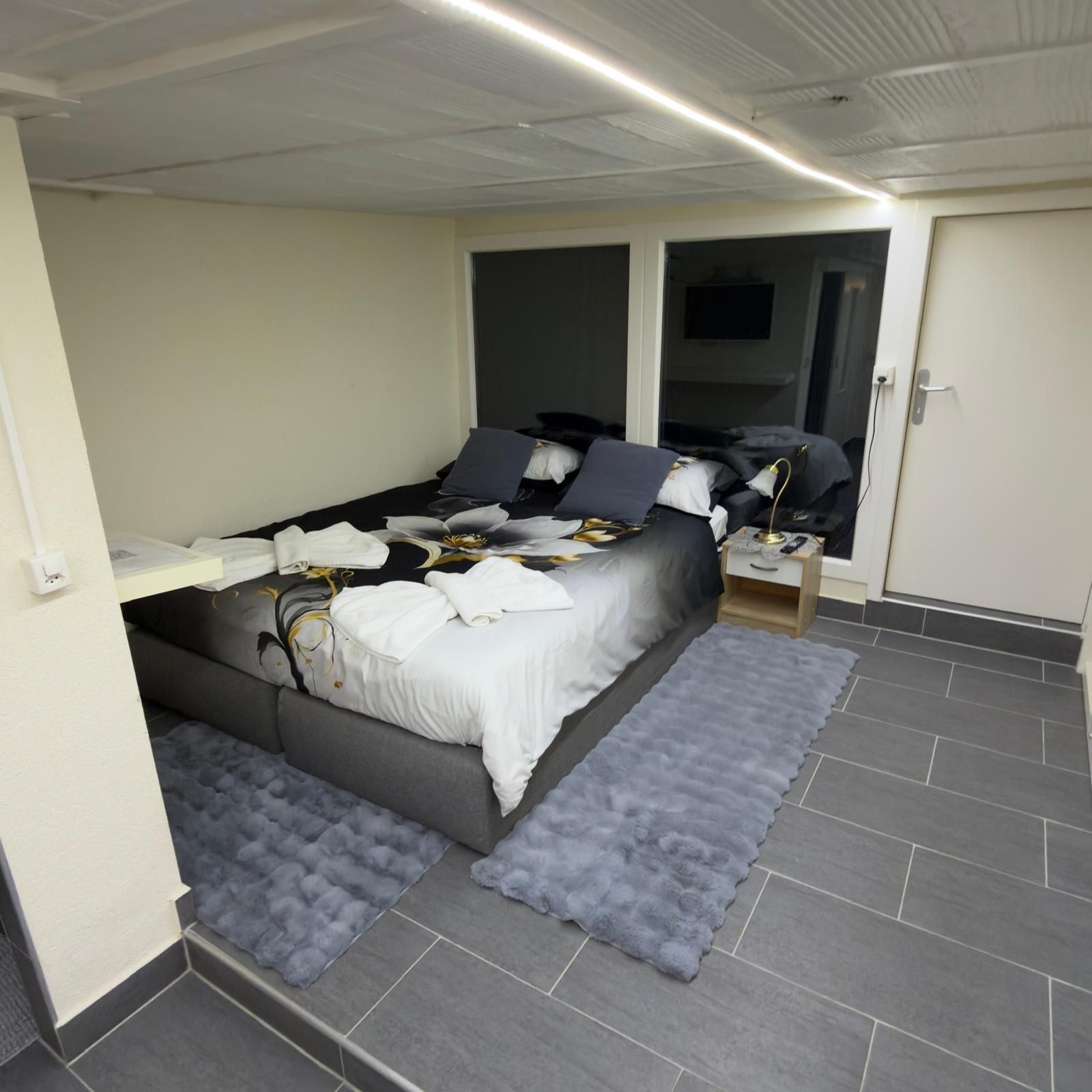 A bedroom with a bed, bedside tables, a mirror, and a wardrobe.