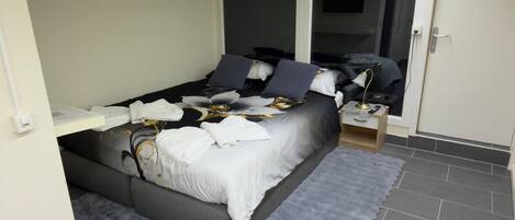 A bedroom with a bed, bedside tables, a mirror, and a wardrobe.