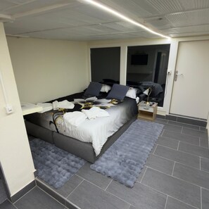 A bedroom with a bed, bedside tables, a mirror, and a wardrobe. - New Listing (Bussigny)
