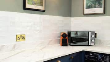 A kitchen with a microwave, a washing machine, and two framed artworks on the wall.