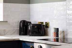 Une cuisine avec un grille-pain noir, une machine à café noire et un étagère à épices.