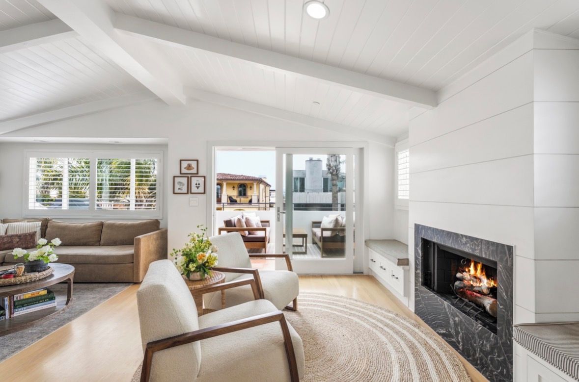 A spacious living room with a fireplace, a sofa, a coffee table, and a view of the outdoors.