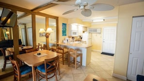 A dining area with a wooden table and chairs, a ceiling fan, and a kitchen in the background. - Beachside Getaway: Studio Starboard Villa at Sea Club IV by Capital Vacations (Daytona Beach Shores)