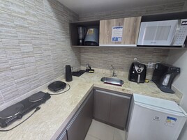 Cozinha equipada com micro-ondas, máquina de café e pequena geladeira.