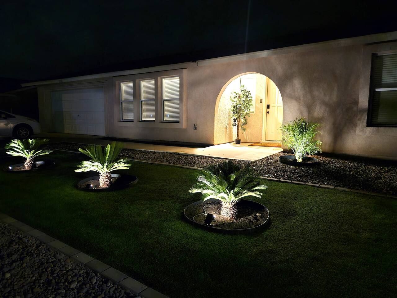 Un camino de entrada residencial con césped artificial, plantas en macetas y un garaje.