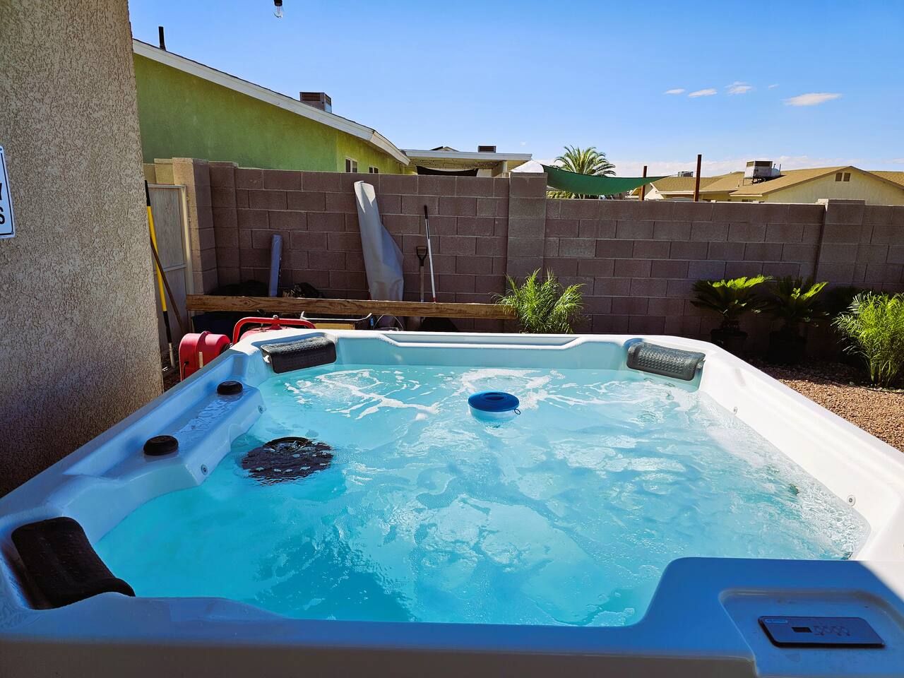 A hot tub with a brick wall and a green building in the background.
