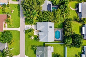 Un quartier résidentiel où se trouve une maison dotée d’une piscine, entourée d’une végétation luxuriante et de palmiers.