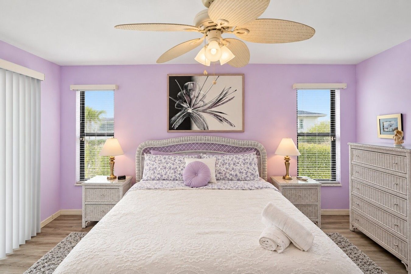 A bedroom with a bed, two bedside tables, a ceiling fan, and a window with blinds.