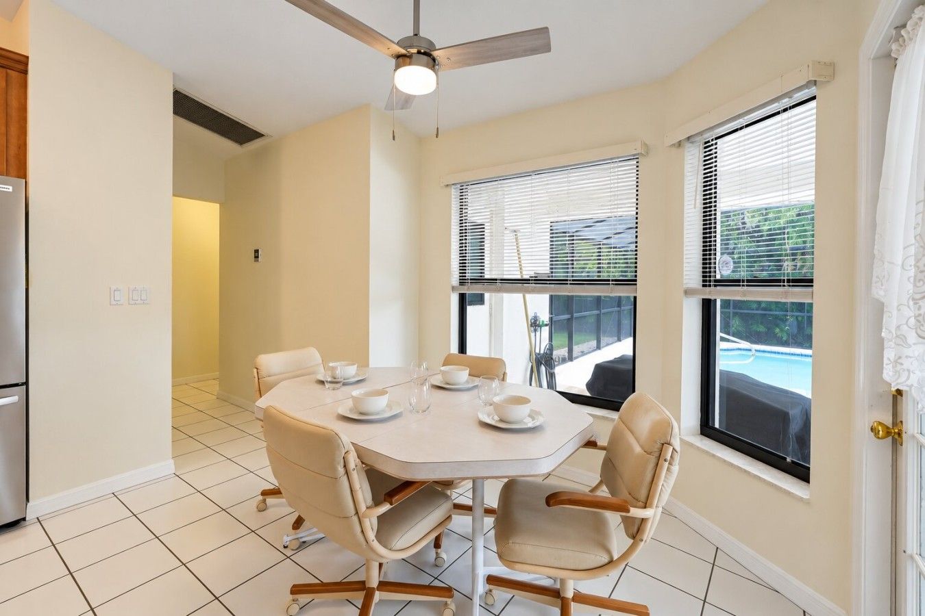 A dining area with a round table, six chairs, and a ceiling fan.
