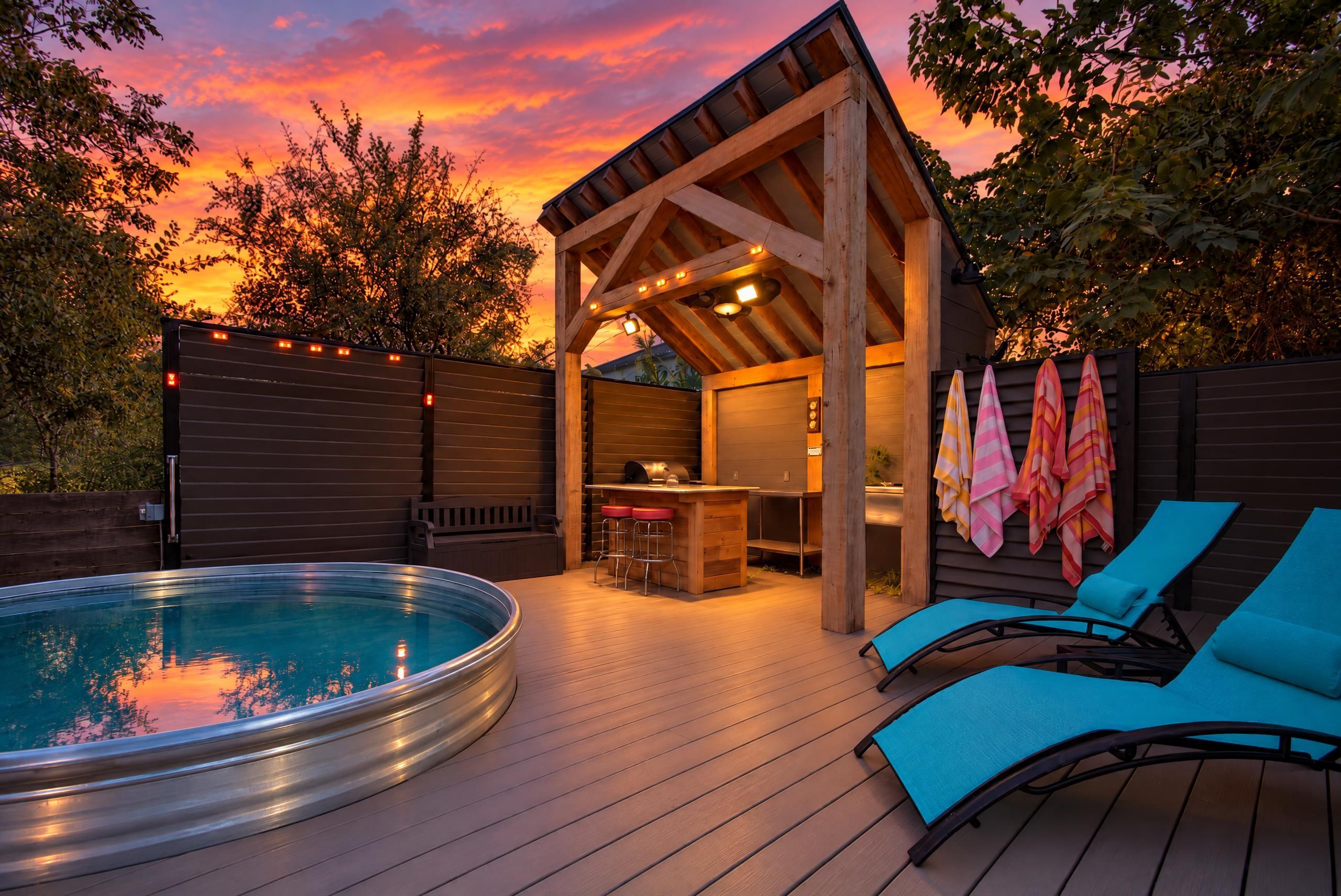 A hot tub with a wooden deck, a covered seating area with a bar, and lounge chairs.