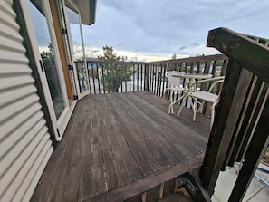 A wooden deck with a table and chairs, a railing, and a view of the surrounding area. - Handy quiet and spacious space to relax and unwind walkable to town and beach (Motueka)