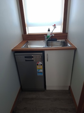 A compact kitchen with a built-in dishwasher, a stainless steel sink, and a window above the sink. - Handy quiet and spacious space to relax and unwind walkable to town and beach (Motueka)