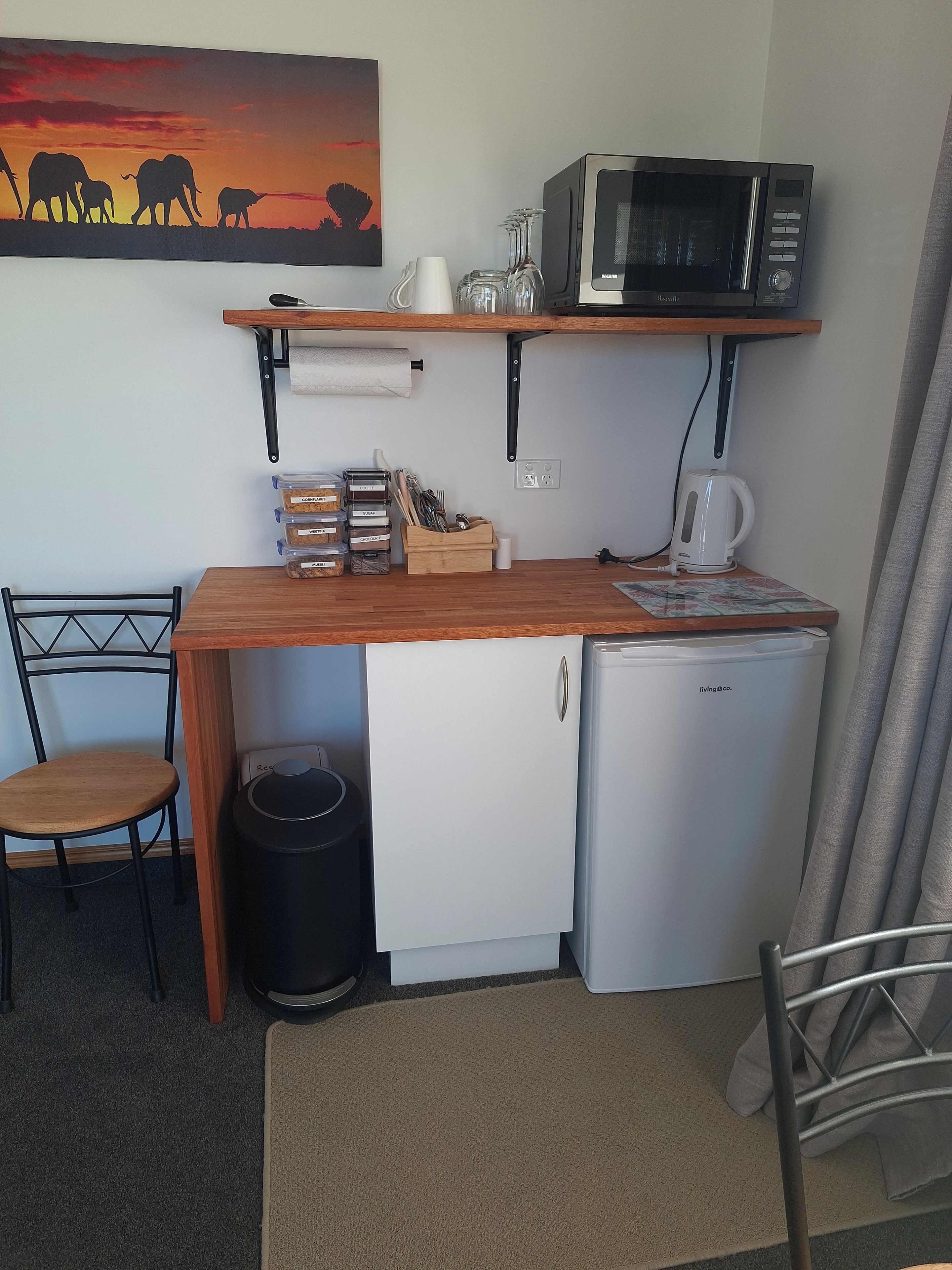 Uma cozinha compacta equipada com micro-ondas, mini-geladeira e cafeteira.
