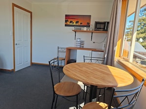 A room with a dining table, chairs, a microwave, and a painting on the wall. - Handy quiet and spacious space to relax and unwind walkable to town and beach (Motueka)