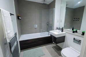 Et moderne badeværelse med bruseniche, en hvid vask og toilet.