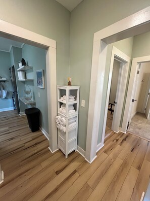 Ein Flur mit einem weißen Schrank, Holzdielen und einer Tür zu einem weiteren Raum.