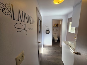 A hallway with a wall-mounted sign that reads 'LAUNDRY Self-serve' and another sign that says 'Hone self joy.' - Coming to town for a weekend of games? 3Br/2Ba home - pet friendly w/ RV Parking (Selah)