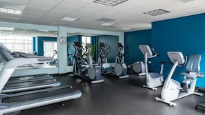 Ein Fitnessstudio mit Laufbändern, Crosstrainern und stationären Fahrrädern.
