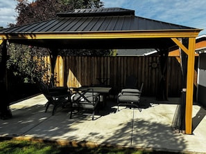 En overdækket terrasse med et bord og stole.