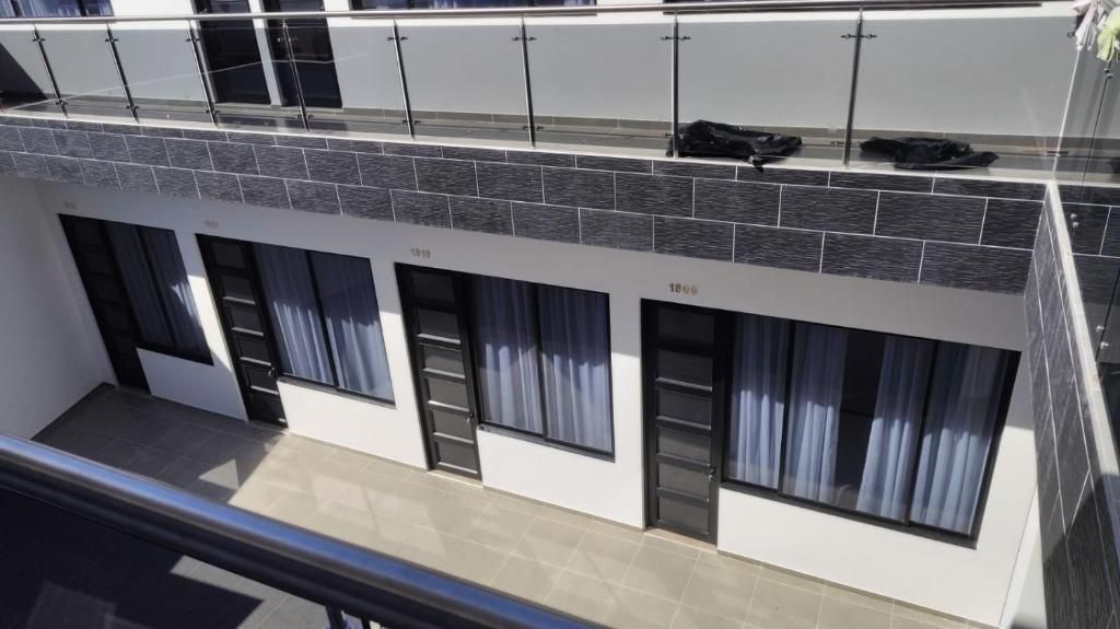 Un bâtiment moderne doté d’un toit plat, de grandes fenêtres et d’un balcon avec une balustrade.