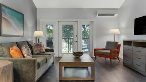 Un salon moderne avec un canapé, une table basse, un fauteuil et un téléviseur.