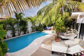 Piscina com espreguiçadeiras e deck de madeira.