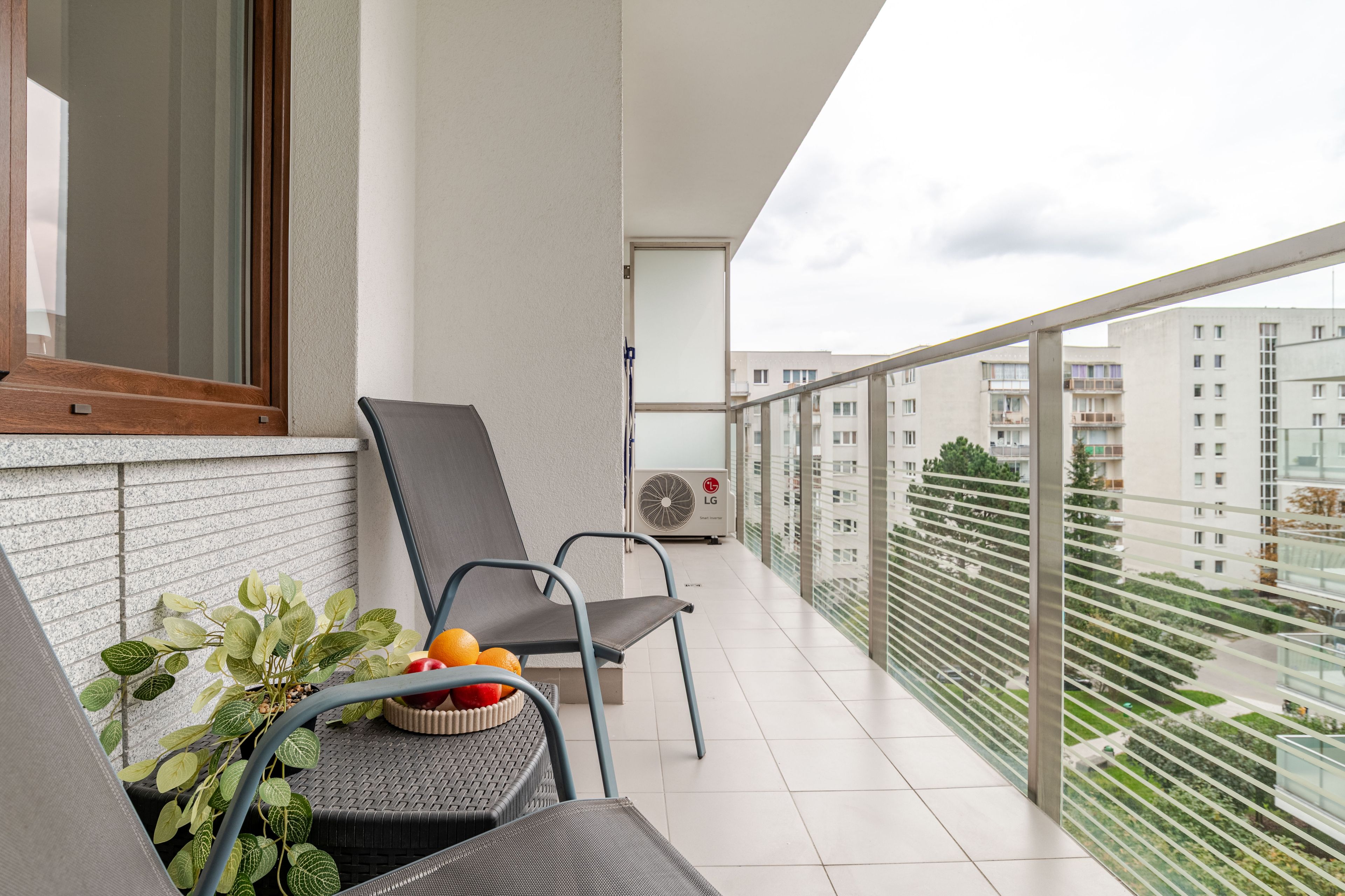 Ein Balkon mit zwei Stühlen, einem Tisch mit Obst und einem Blumentopf.