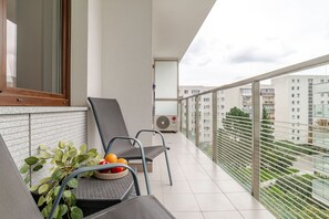 A balcony with two chairs, a table with fruit, and a potted plant. - Dereniowa 10 Apartment by StayFirst.pl (Warszawa)