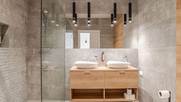 Une salle de bain moderne avec une douche à parois de verre, deux vasques et un meuble-lavabo en bois.