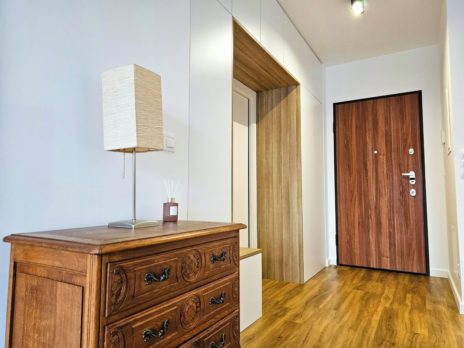Eine hölzerne Kommode mit Schubladen, eine Lampe und ein kleiner Behälter mit Schilferdiffusor.