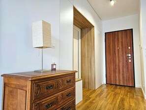 A wooden dresser with drawers, a lamp, and a small container with reed diffusers. - Dereniowa 10 Apartment by StayFirst.pl (Warszawa)