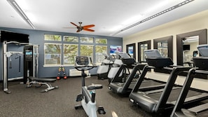 Ein Fitnessstudio mit Laufbändern, Crosstrainern und Gewichten.